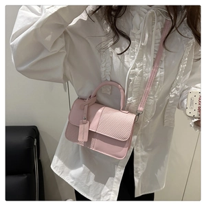 Vue détaillée du sac rose avec rabat à texture tissée et étiquette mode sur modèle