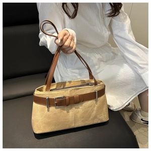 Detail of khaki suede tote bag with brown leather straps shown in lifestyle setting