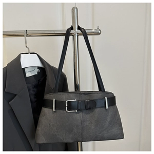 Detail of dark grey suede shoulder bag featuring a black belt strap and silver buckle