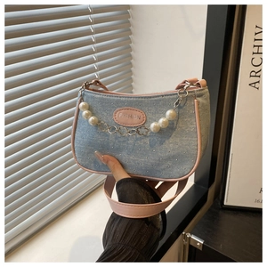 Detail of blue denim mini bag with pink leather trim and decorative pearl metal chain