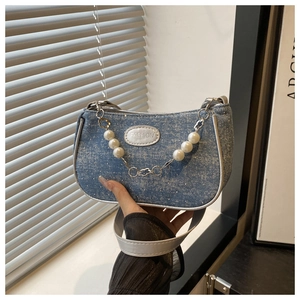 Detail of blue denim shoulder bag with white piping and elegant pearl chain pendant