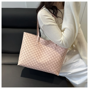 Detailed side view of a large nude pink tote bag with brown M-letter pattern on a shoulder