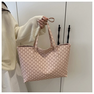 Detailed side view of pink tote bag with brown M-letter monogram print and top handles