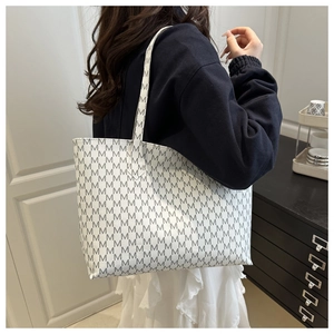 Detail of large tote bag with repetitive M letter pattern and long shoulder handles
