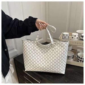 Large tote bag with M letter monogram print in grey being held in a stylish indoor setting