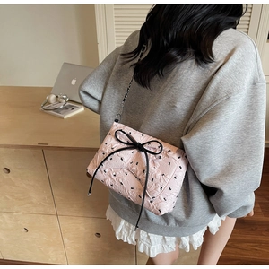 Pink quilted crossbody bag with large black bow and cute prints shown in lifestyle setting