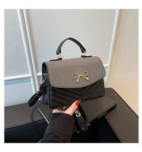 Détail du rabat en tissu à rayures et boucle nœud doré sur le sac à main matelassé