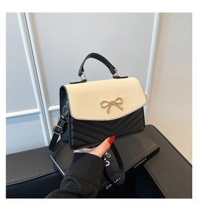 Détail d'un sac bicolore tissé avec boucle nœud doré et matelassage chevron chic