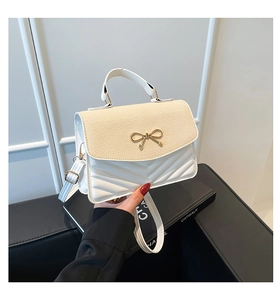 Détail d'un sac à main matelassé avec rabat tissé beige et fermoir noeud papillon doré