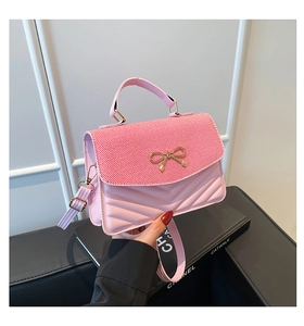 Détail du petit sac rose avec rayures rouges, nœud doré et texture matelassée en V
