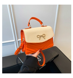 Détail du sac orange en cuir avec rabat tressé beige et fermoir doré en nœud