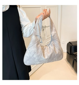 Detail view of silver pleated tote bag showing unique 3D texture and metallic zipper