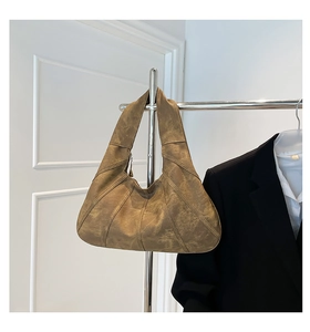 Brown vintage crescent tote bag with stitched panels hanging on a metal hanger
