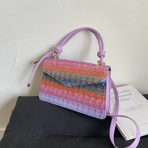 Rainbow woven straw handbag with wavy patterns and purple knotted handle straps
