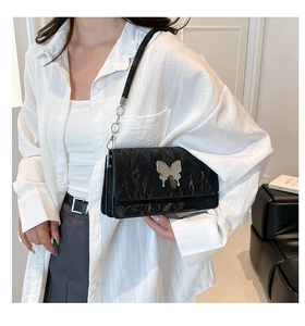 Close-up of black pleated shoulder bag with silver butterfly buckle and chain strap