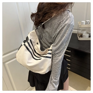 Détail du grand sac cabas rayé montrant le drapé latéral et le bouton pression noir