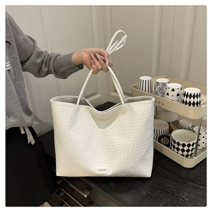 Détail du sac cabas blanc à texture tressée avec fines anses et étiquette mode