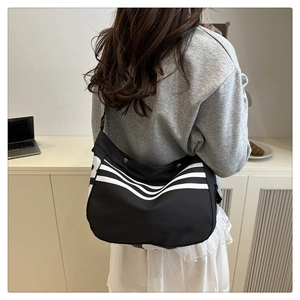 Détail d'un grand sac bandoulière noir avec rayures sportives blanches et sangle large