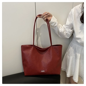 Détail du sac fourre-tout rouge foncé à texture tressée et fines bandoulières