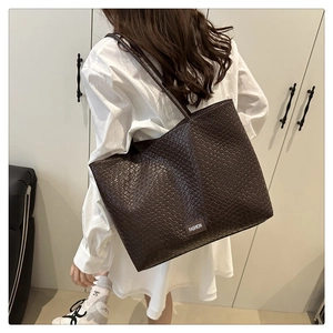 Détail de la texture tressée marron foncé sur le grand sac cabas avec bandoulière