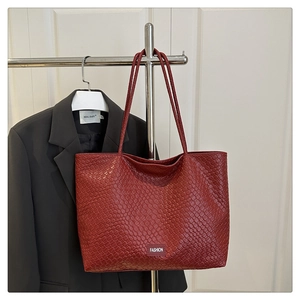 Détail du grand sac cabas tressé rouge foncé avec étiquette de mode près d'un blazer