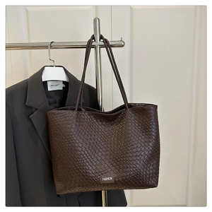Détail d'un cabas tressé marron foncé montrant la texture cuir et le logo Fashion