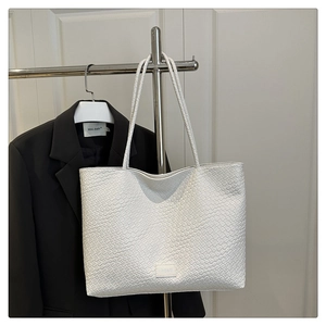 Gros plan détaillé du sac cabas blanc tissé avec fines bretelles et écusson du logo