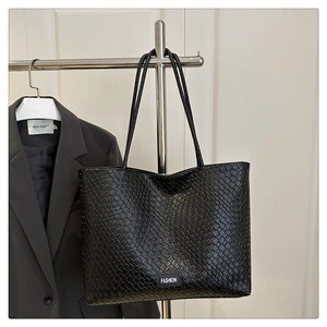 Détail d'un grand sac cabas noir tissé avec logo Fashion suspendu sur un cintre en métal