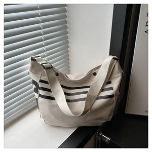 Détail du sac bandoulière beige minimaliste avec rayures noires et large sangle réglable