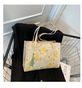 Detail of floral jacquard tote bag with elegant embroidery and green tassel ornament