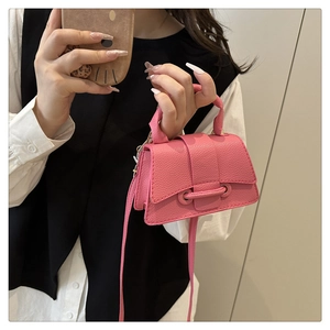 Detailed shot of pink pebble grain leather texture and gold buckle on a mini handbag