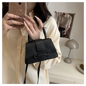 Close-up of black lychee-textured leather mini hourglass handbag with sleek metallic details
