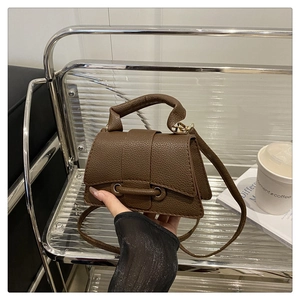 Detail view of a brown lychee pattern leather mini handbag with top handle and strap