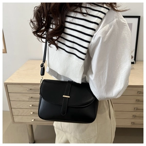 Detail of a vintage black crossbody bag featuring a smooth leather finish and gold metal clasp