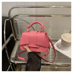 Detail of bright pink mini bag with litchi texture and metal ring buckle design