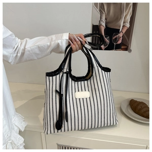 Close-up of canvas striped tote bag with leather trim and dual handles for women