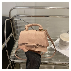 Detail of light pink mini handbag with pebbled leather texture and unique flap closure