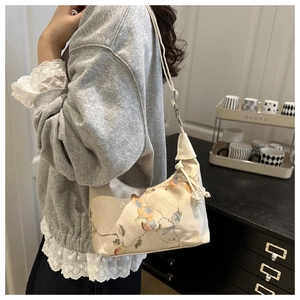 Detail of silk crescent underarm bag with traditional floral embroidery and bead charm