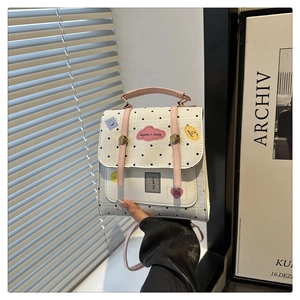 Detailed view of white polka dot bag with lace trim, pink handles and creative badges