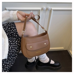 Detail of brown lychee grain leather shoulder bag with gold rivets and fashion logo