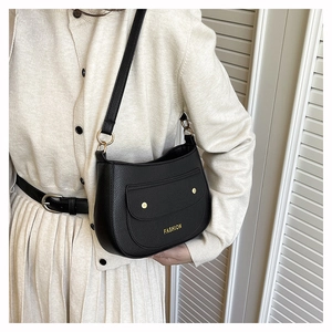 Close-up of black lychee grain leather crossbody bag with golden metal hardware detail