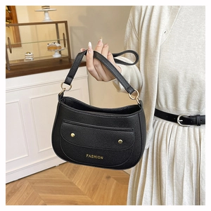 Detail of black pebbled leather hobo bag with front pocket and gold buckle accents