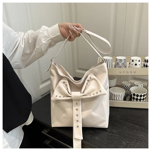 Détail d'un sac à bandoulière en similicuir crème avec nœud élégant et rivets argentés