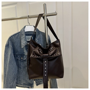 Detail of dark brown PU leather bag featuring a large bow and sparkling silver rhinestones