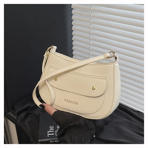 Close-up of cream crescent shoulder bag with lychee texture and gold fashion lettering