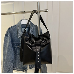 Detail of black PU leather tote bag featuring a sparkling rhinestone bow decoration