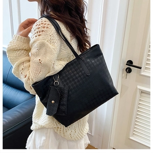 Detailed houndstooth embossing on a large black faux leather tote bag with small hanging pouch