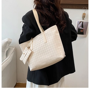 Detail of cream houndstooth tote bag with matching mini pouch shown on shoulder