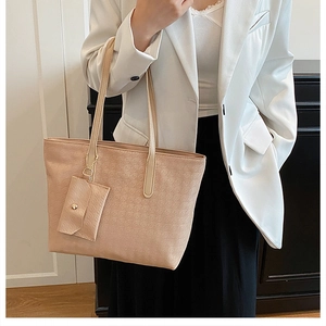 Classic beige tote bag with a small coin purse charm shown on a female model