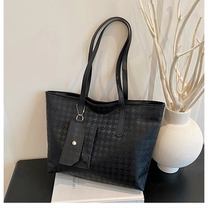 Detail of black houndstooth tote bag with a small matching envelope pouch and gold chain